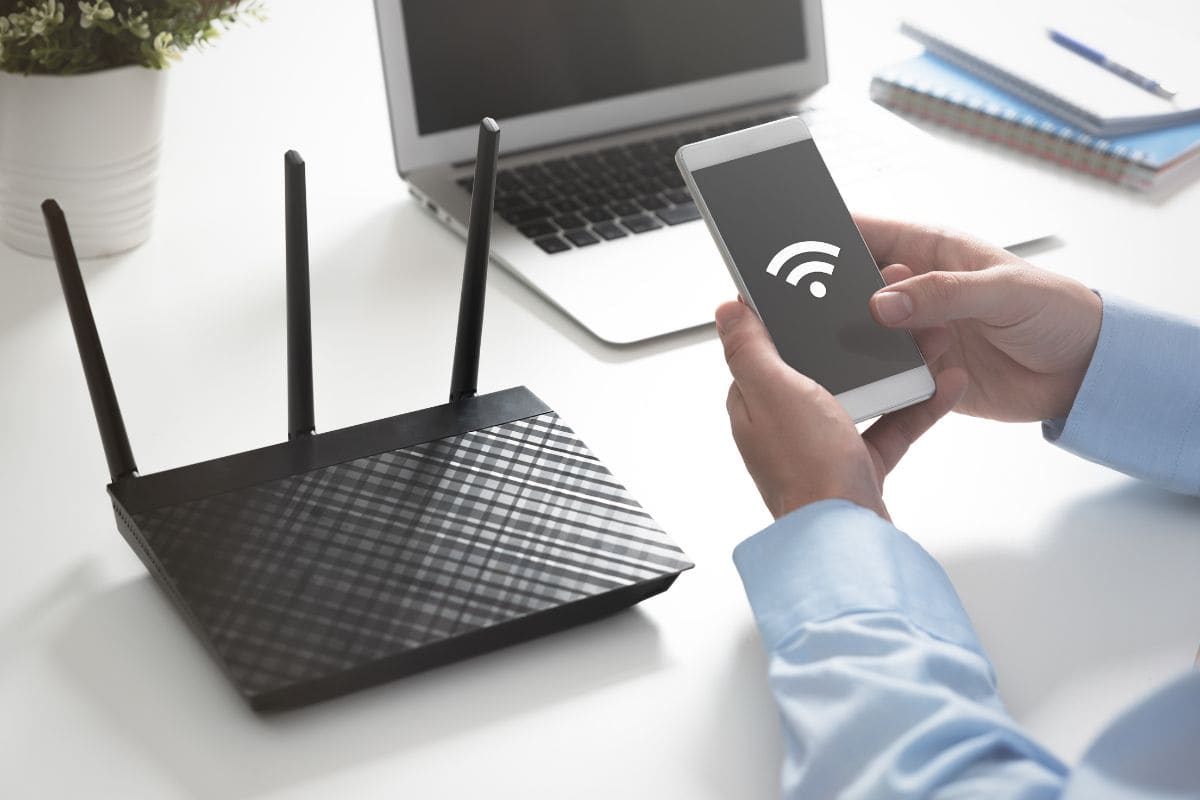router wi-fi, con mani uomo che controlla wi-fi sullo smartphone e pc spento