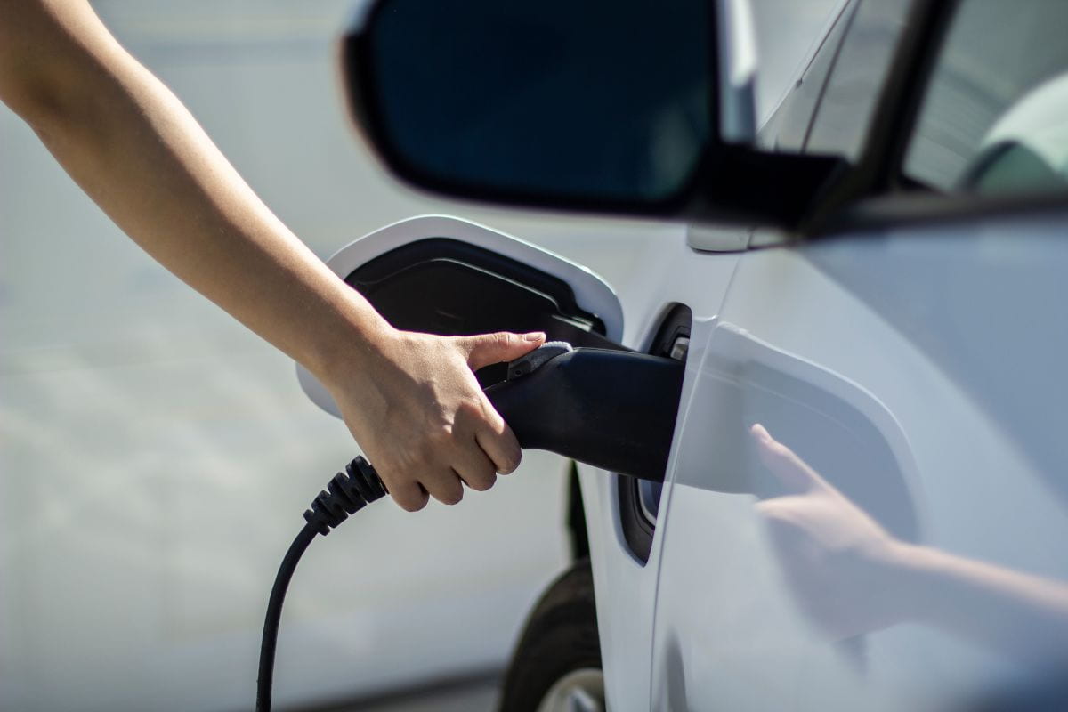 mano che mette ricarica auto elettrica bianca
