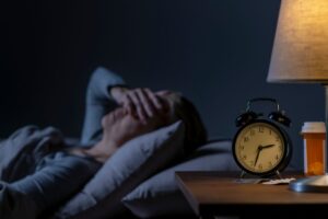 donna che soffre si insonnia con sveglia e lampada sul comodino